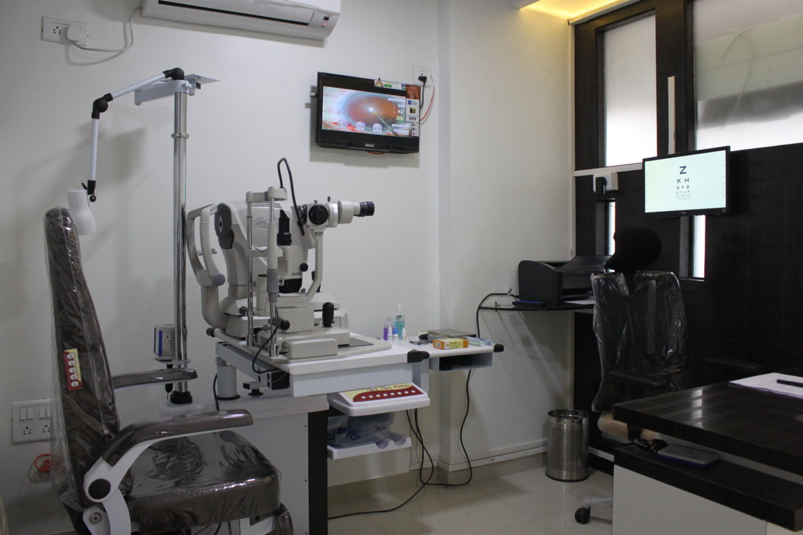 Refraction and slit-lamp consultation suite at Insight Institute pairing an autorefractor with a Lenovo corneal topography map on the desktop display